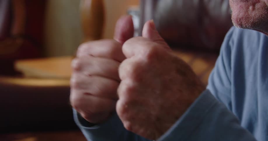 Hands of an older man forming fists as he cheers out of excitement