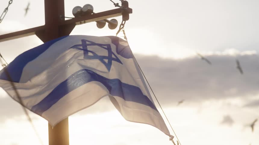 An israeli flag on a mast waving in the wind