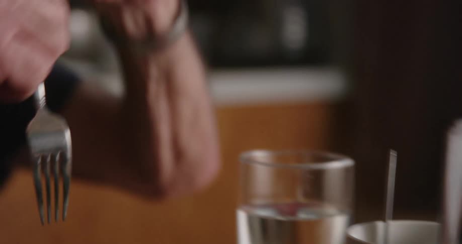 Man eating a meal picks up a fork from a white ceramic cup
