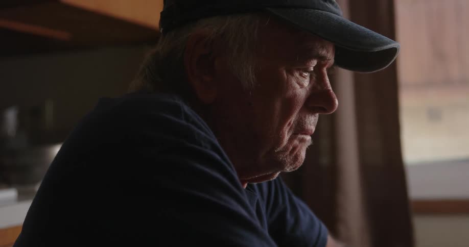 An old man thinking while sitting indoor at midday
