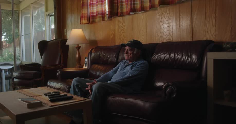 Elderly person sitting on the couch watching and gesturing excitedly and smiling