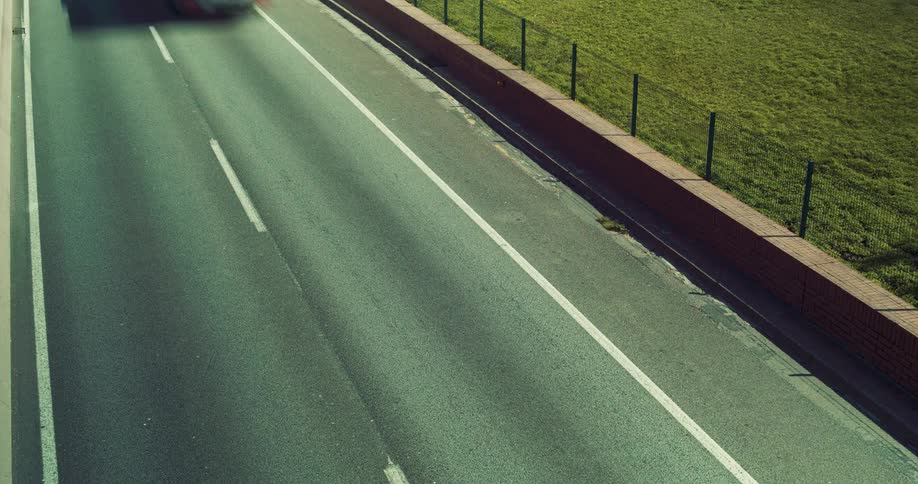 An overhead shot of sped up cars and trucks driving on a highway.