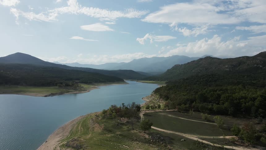 Landscape of a central river with trees along its banks and a mountain range in the background