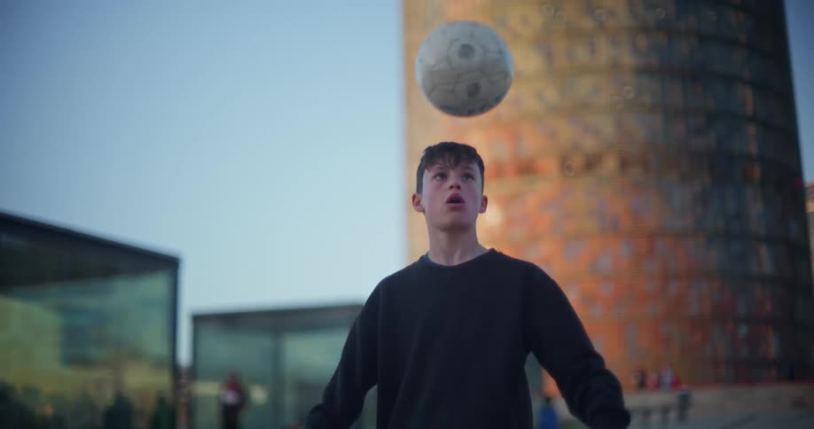 Boy bounces a soccer ball in the city streets
