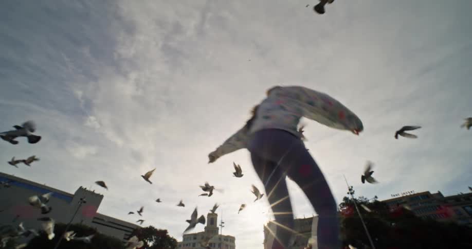 Pigeons take off as a woman roller-skates past