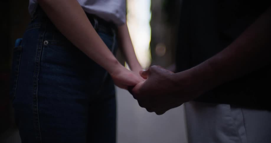 Close up in a city street of a couples hands as one caresses the other