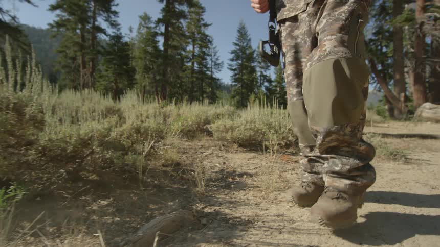 A man wearing camouflage is hiking on a sunny day