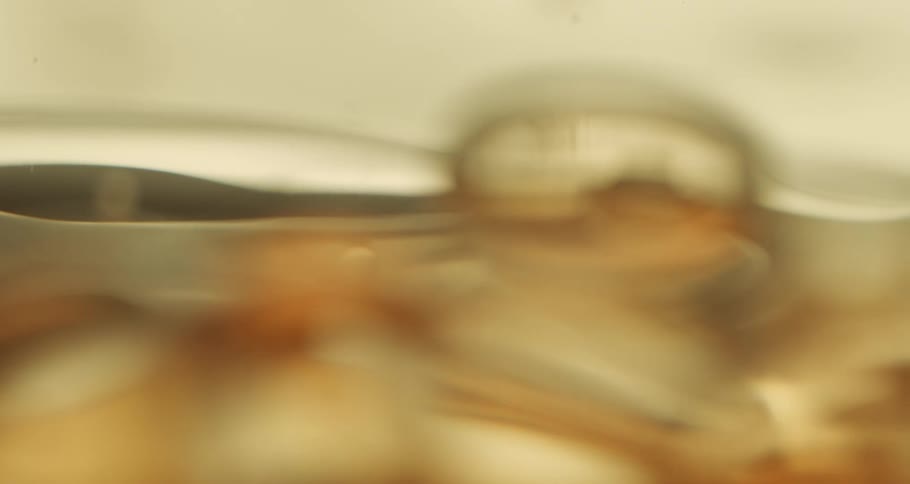 A golden sticky liquid reflects on its surface