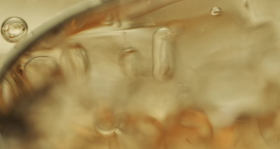 Air bubbles slowly move through a thick yellow golden liquid