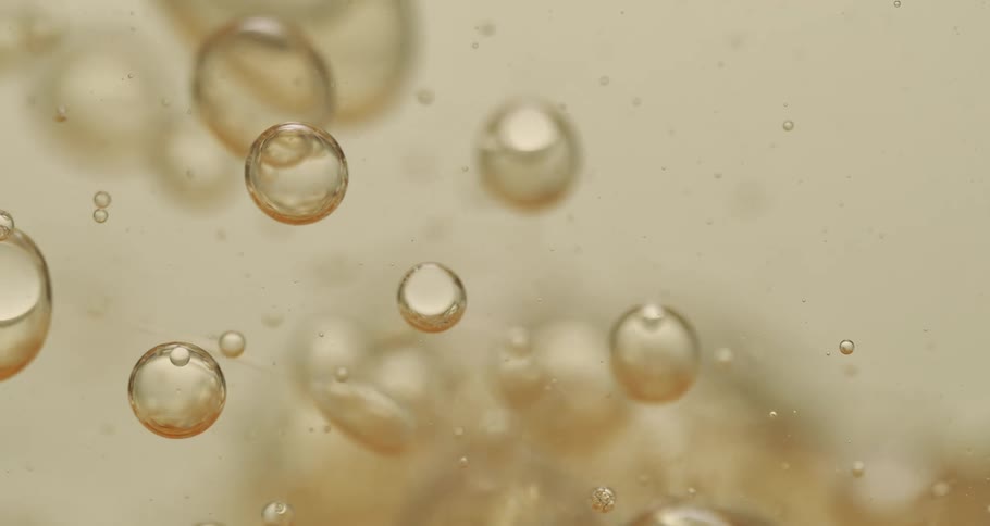 Bubbles of various sizes float through carbonated beverage