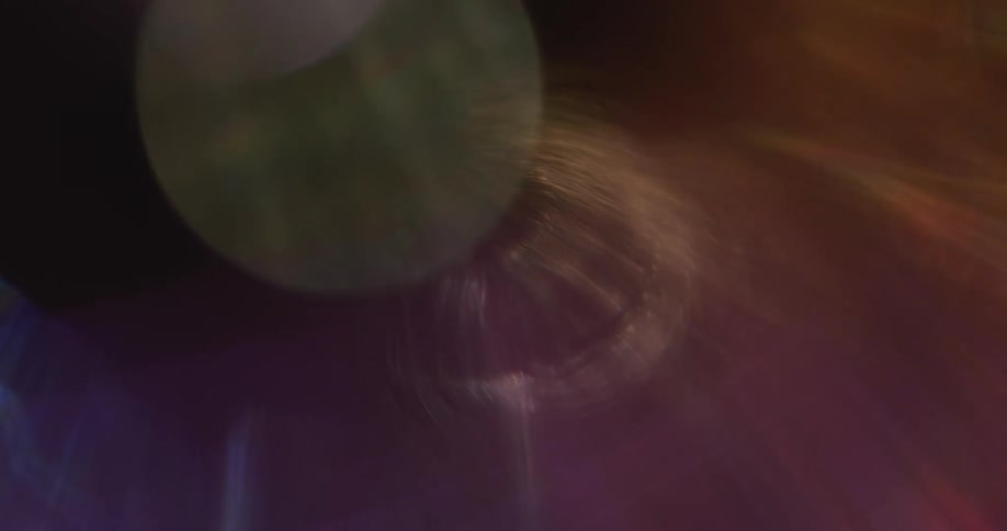 Colorful lights reflect and flare on a lens against a black background