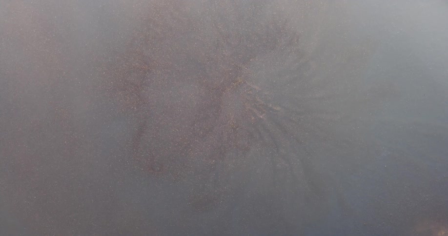 A clouded liquid slowly files with glittery veins raising to the surface with a sudden explosion of solid gel like paint when it reaches the surface