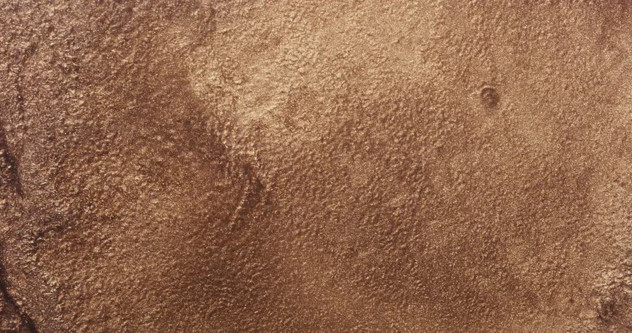 Golden glitter and sand with water flowing through it as it empties and then becomes shaken
