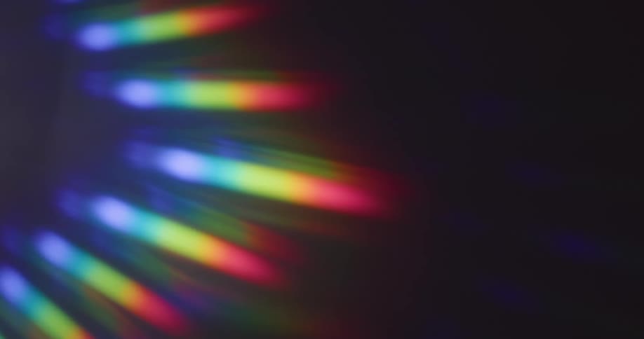 Glowing rainbow colored stripped lines of light shine in the darkness as they fade in and out