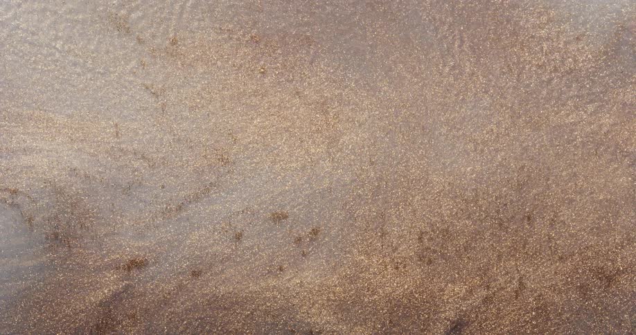 Gold and brown particles flowing and rippling like a liquid