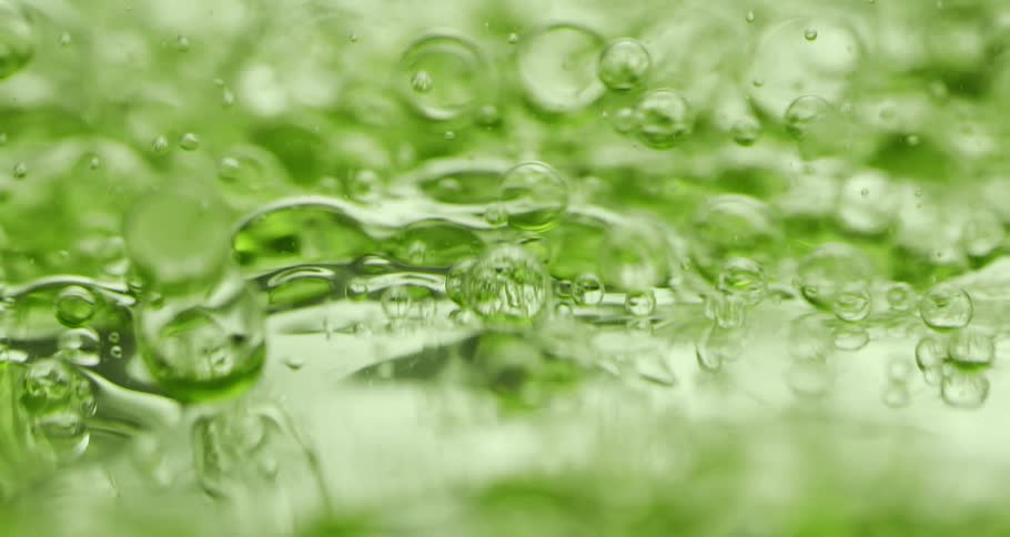 Orbs and bubbles float and move through a clear lime green liquid