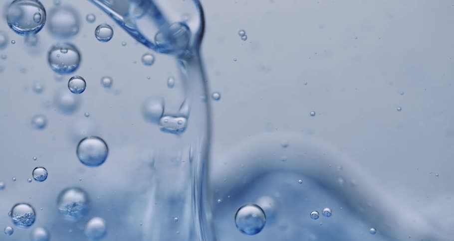 Light shines on bubbles as they float and move in a clear liquid substance