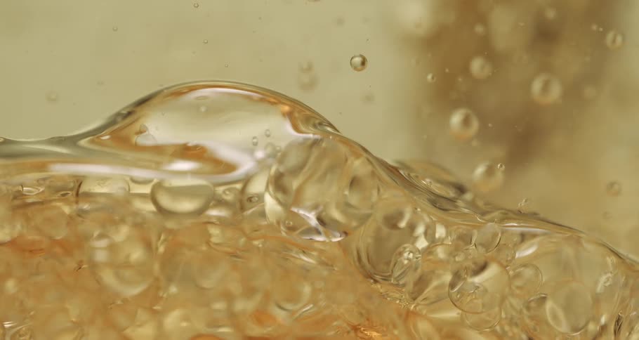 Bubbles float as they rise and move in a clear yellow liquid