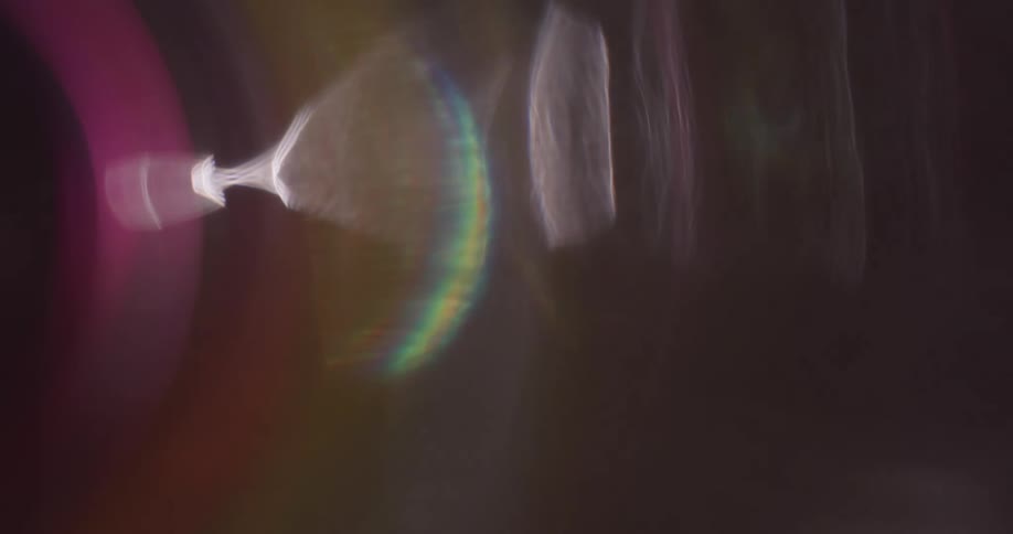 Colorful lights reflect and flare on a lens against a black background