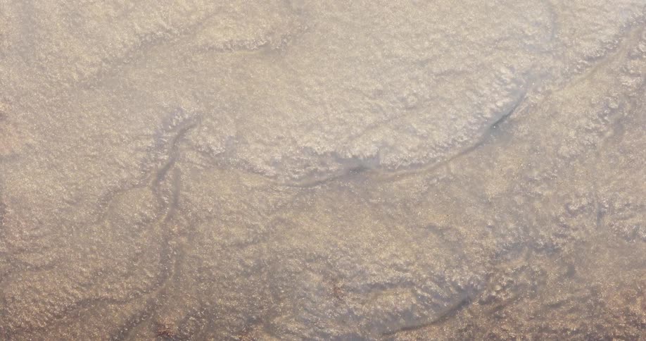 Sand with water flowing over it and rippling downward