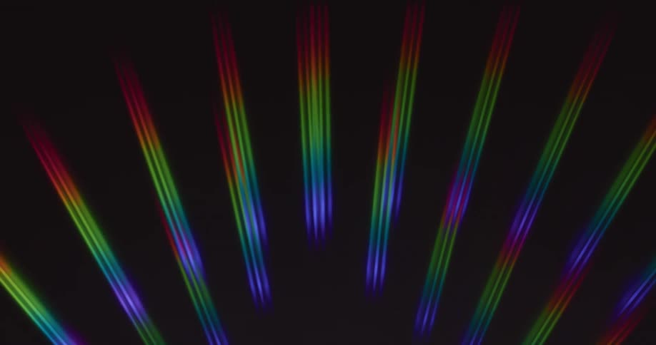 Rainbow colored beams of light slowly moving to the right on a black background