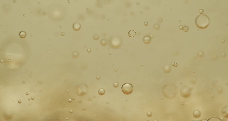 Air bubbles slowly move through a thick yellow liquid