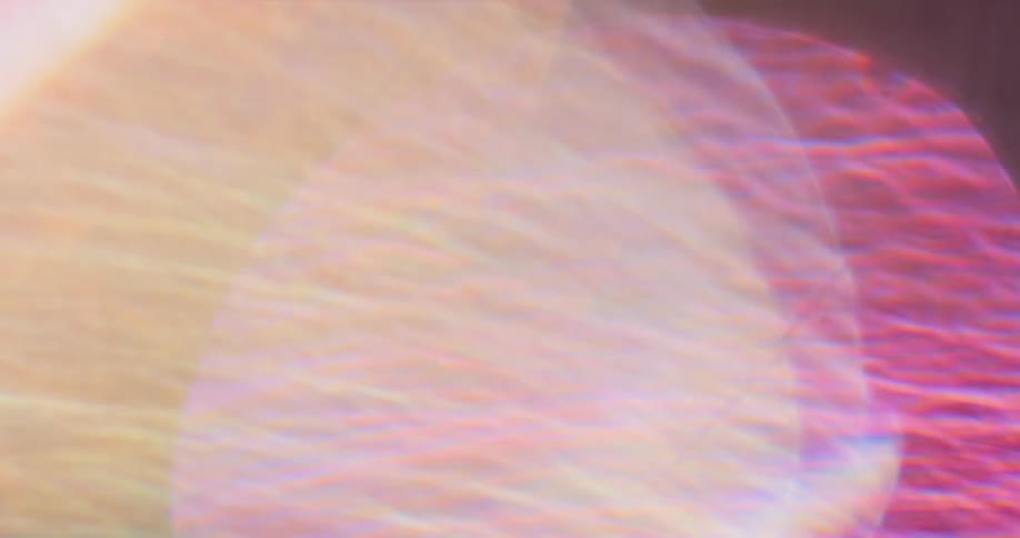 Colorful lights reflect and flare on a lens against a black background