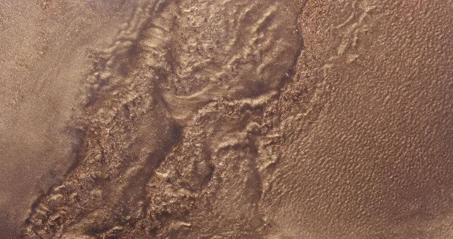 Gold and brown particles flowing and rippling like a liquid