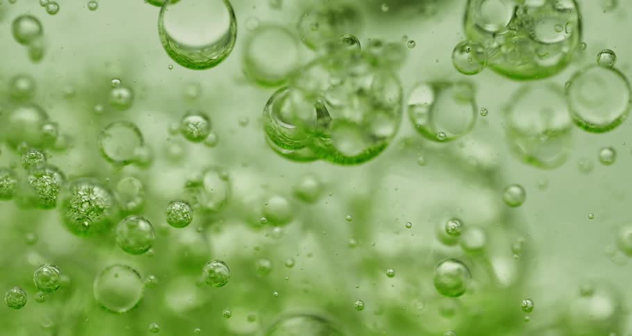 Clear liquid falls against a green background with several bubbles