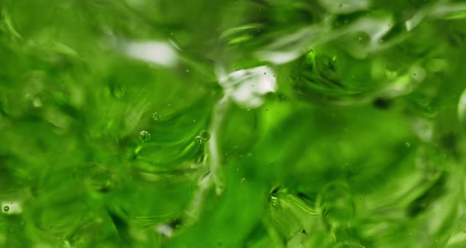 Clear green liquid moving slowly across glass as it bubbles and flows