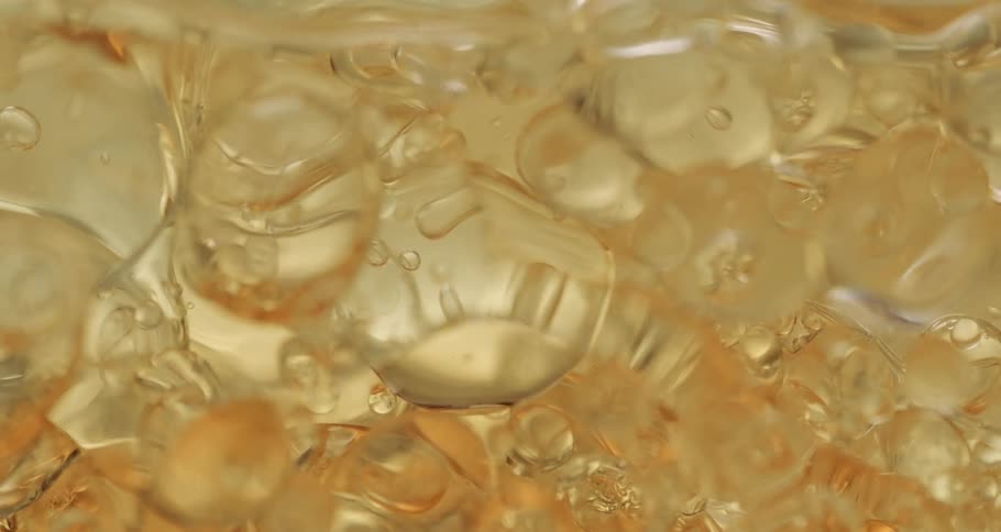 Bubbles of various shapes and sizes move through golden beverage