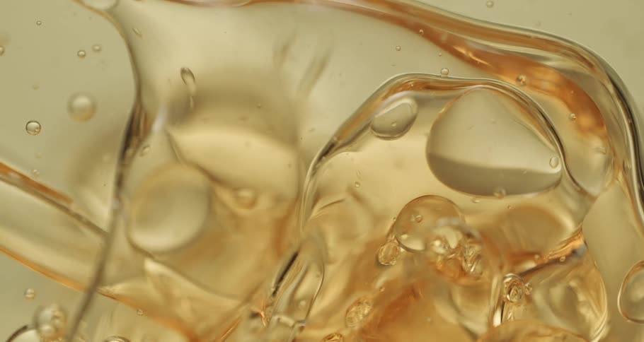 Orbs and bubbles float and move through a clear yellow liquid as a wave of larger bubbles push through