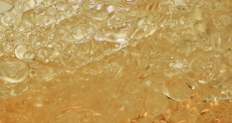 Air bubbles slowly move through a thick yellow liquid