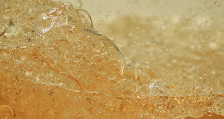 Air bubbles slowly move on the surface of a thick yellow liquid