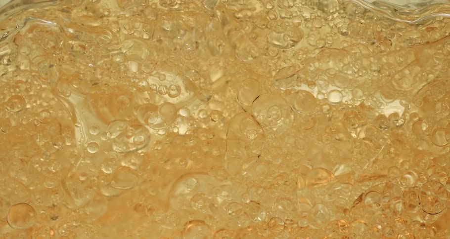 Air bubbles slowly move up a thick yellow liquid