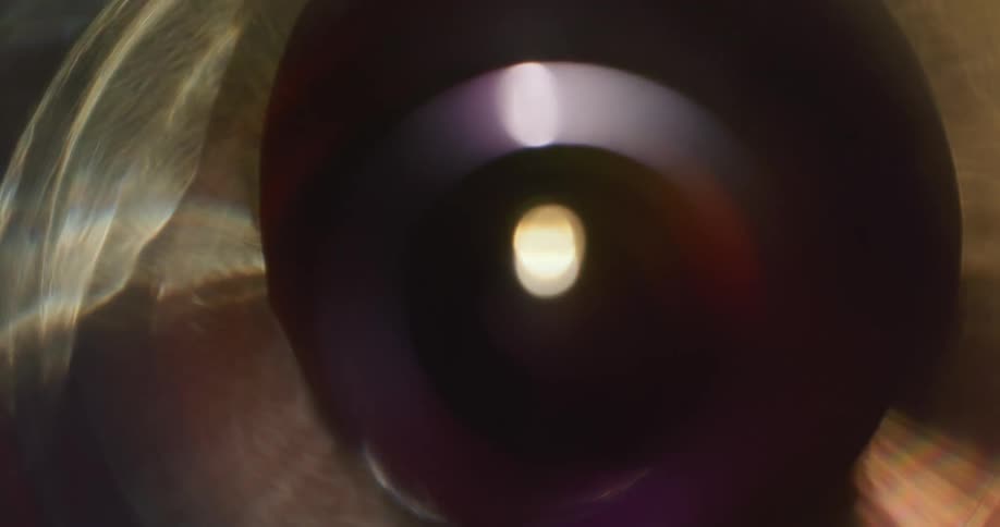 Colorful lights reflect and flare on a lens against a black background
