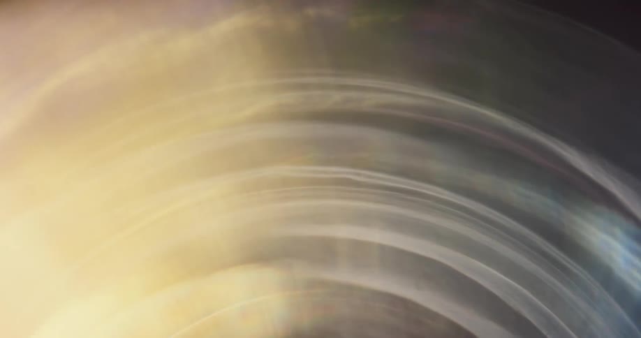 Colorful lights reflect and flare on a lens against a black background