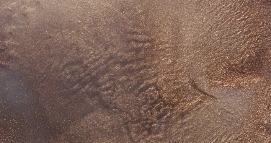 Gold and brown particles flowing and rippling like a liquid