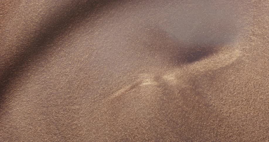 Mauve sand covers golden sand leaving a small dimple on the surface