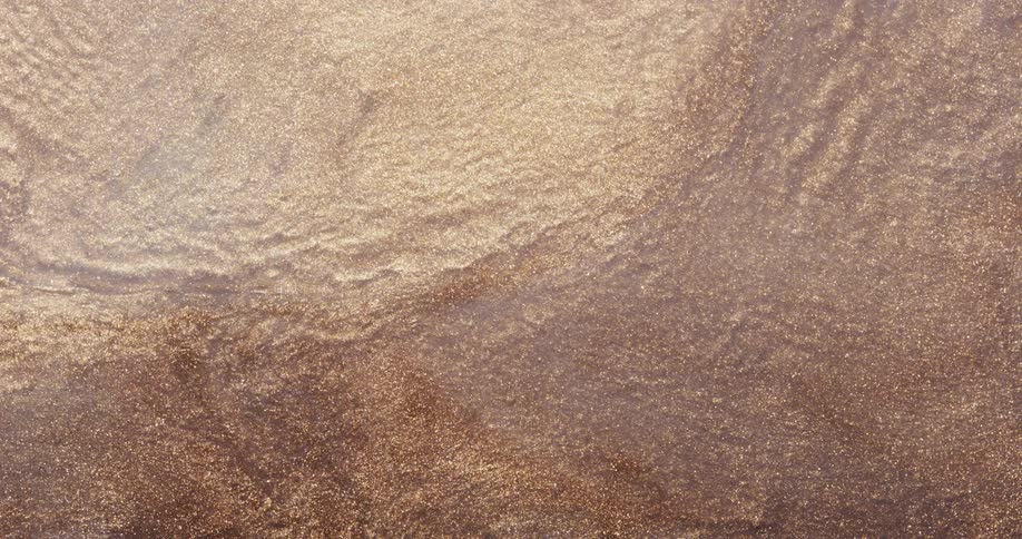 Metallic particles flow to cover pale surface forming waves and a current