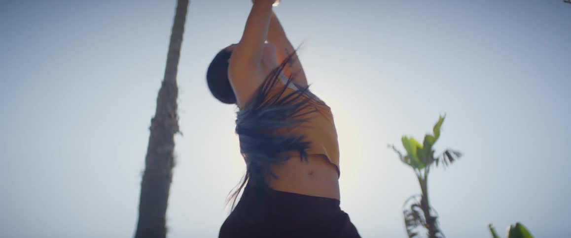 A woman dancing in an outdoor setting with sunlight