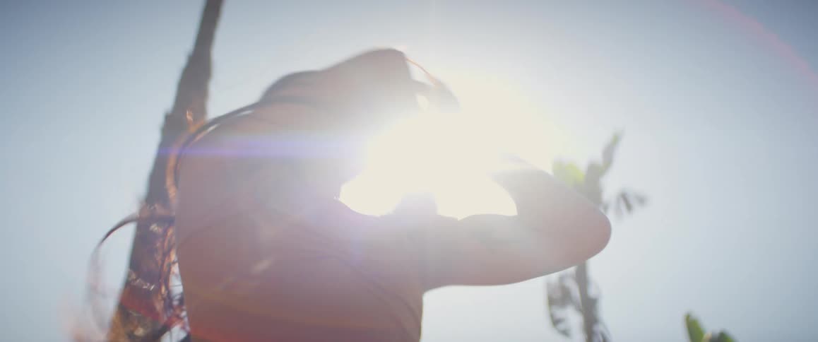 An asian woman dancing with her arms and being illuminated by sunlight
