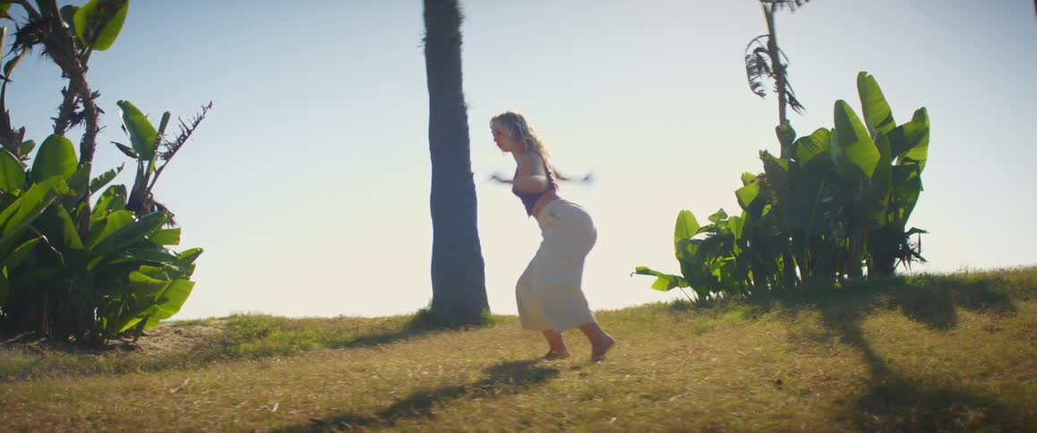 A woman stretching while dancing barefooted at dusk