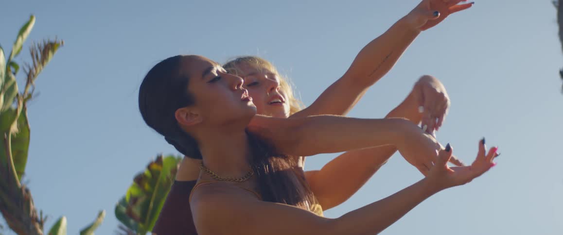 Two women do hand movements outdoors