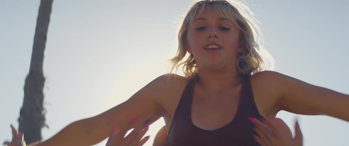 Two young woman gesture with their arms while dancing under the sun
