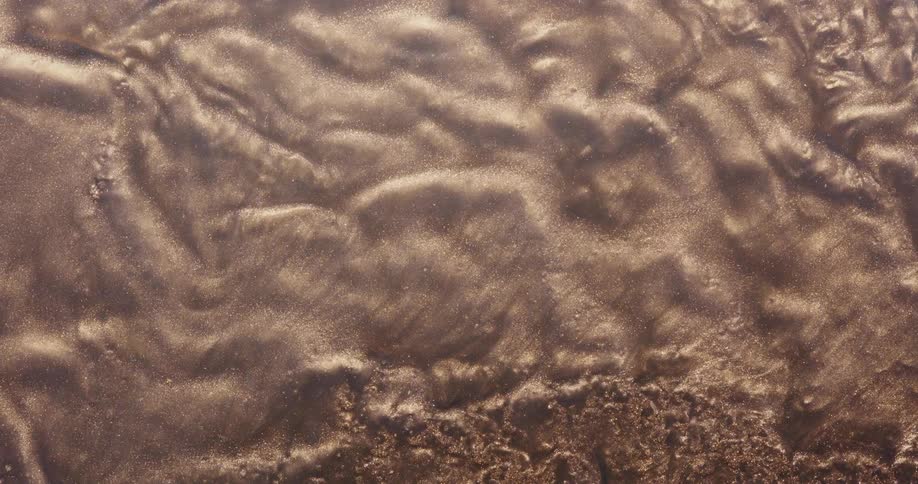 Bronze and brown particles flowing and rippling like a liquid