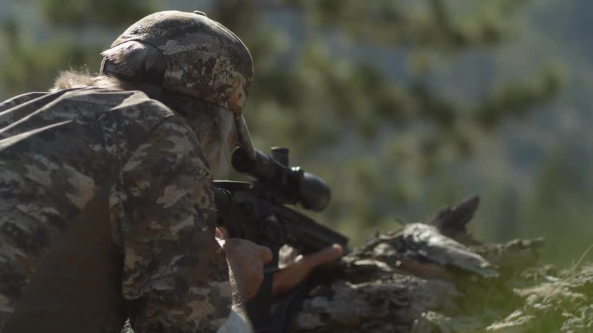 A man is leaning forward aiming a gun