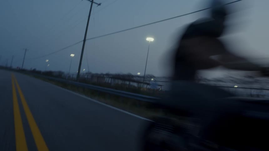 Man rides a motorcycle on a road in the countryside at evening