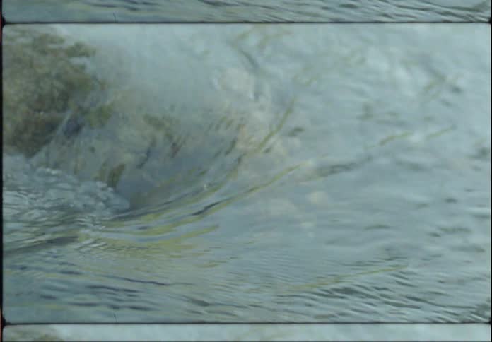 Water flowing on a rock as there is a reflection of the sky