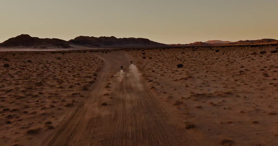 Aerial view of two motorcycles driving on a road in the desert